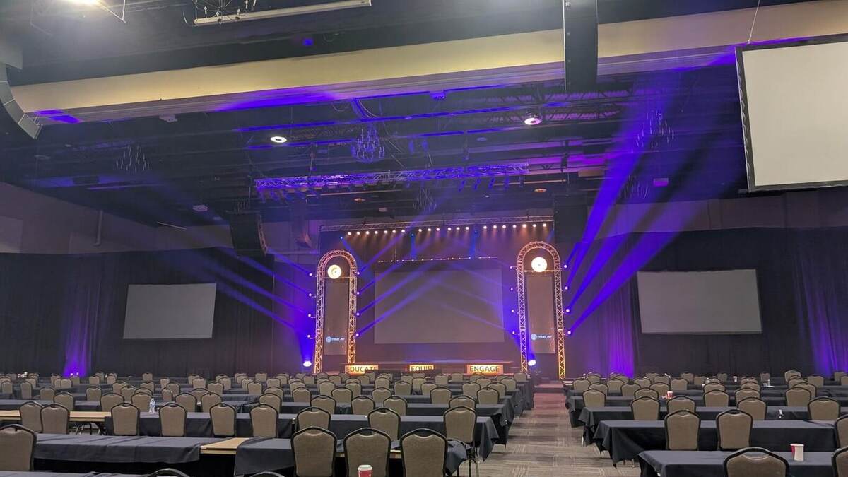 A wide conference general-session room with a custom stage and seating for hundreds