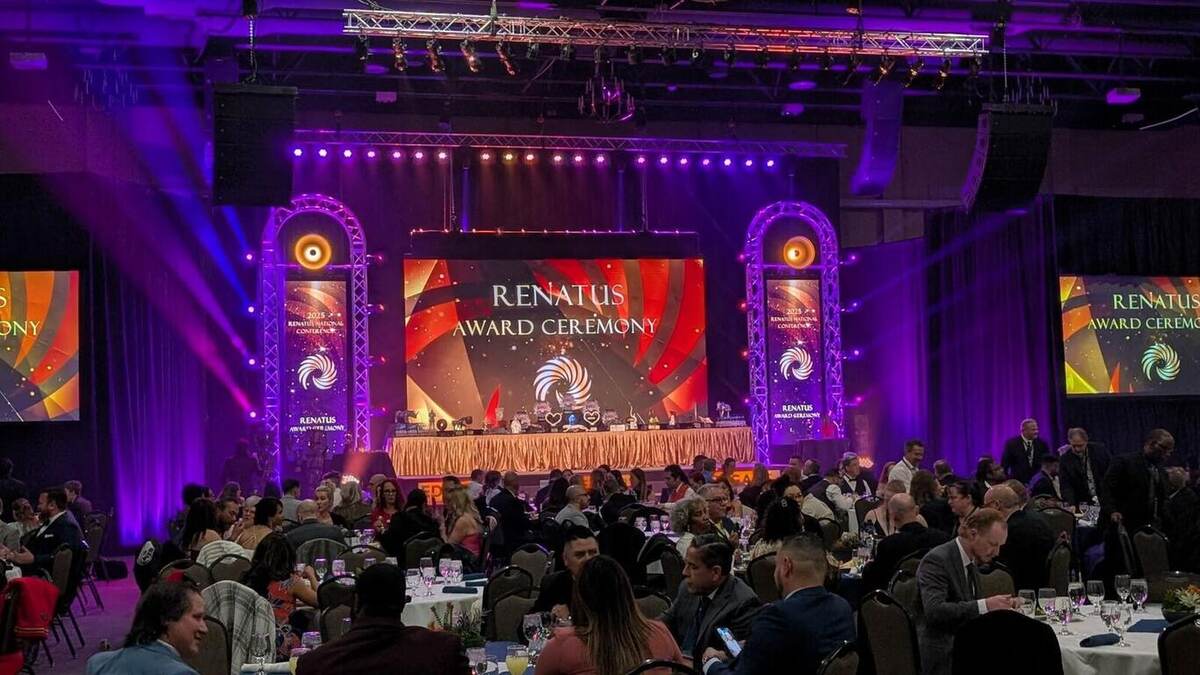 The Renatus awards stage in warm gold and purple light with guests at tables
