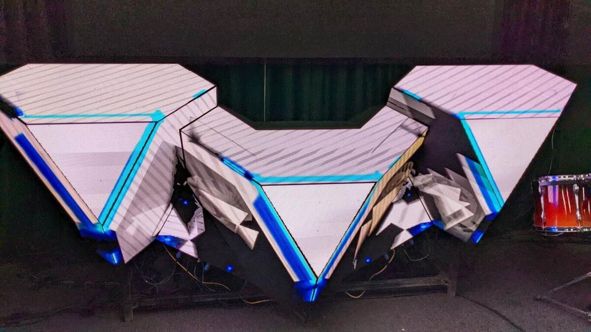 A custom V-shaped scenic stage design with LED trim and blue accent lighting