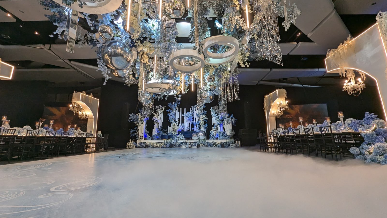 A conference hall transformed into an elegant wedding reception with full lighting and staging