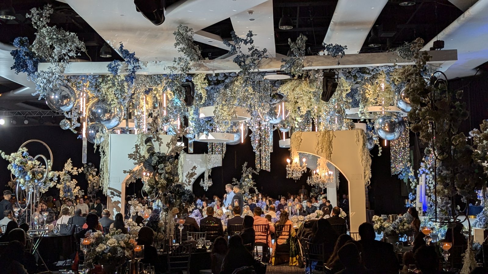 A grand wedding ballroom transformed with floral and full lighting